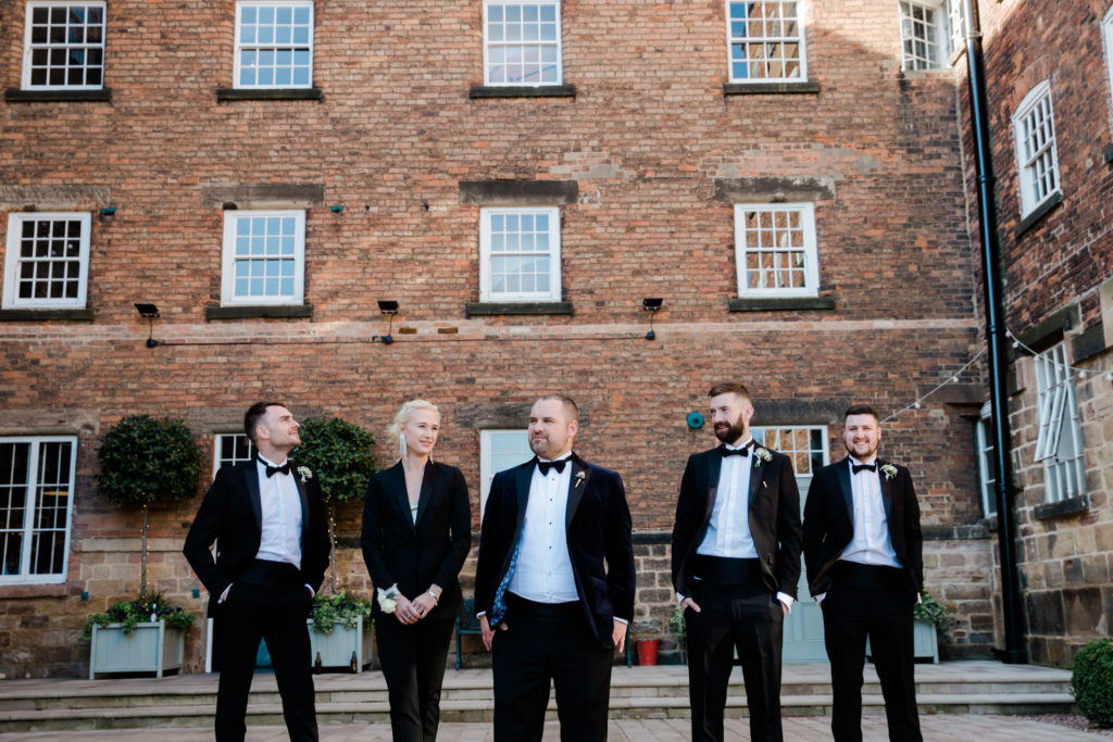 groom and groomsmen wearing tuxedo outside west mill