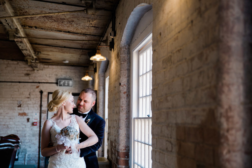 bride and groom snuggle infront of window cotton quarter