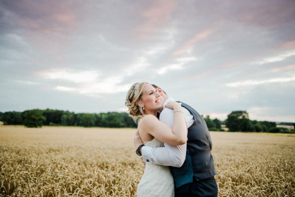 bride and groom embrace in wheat field relaxed natural wedding photography