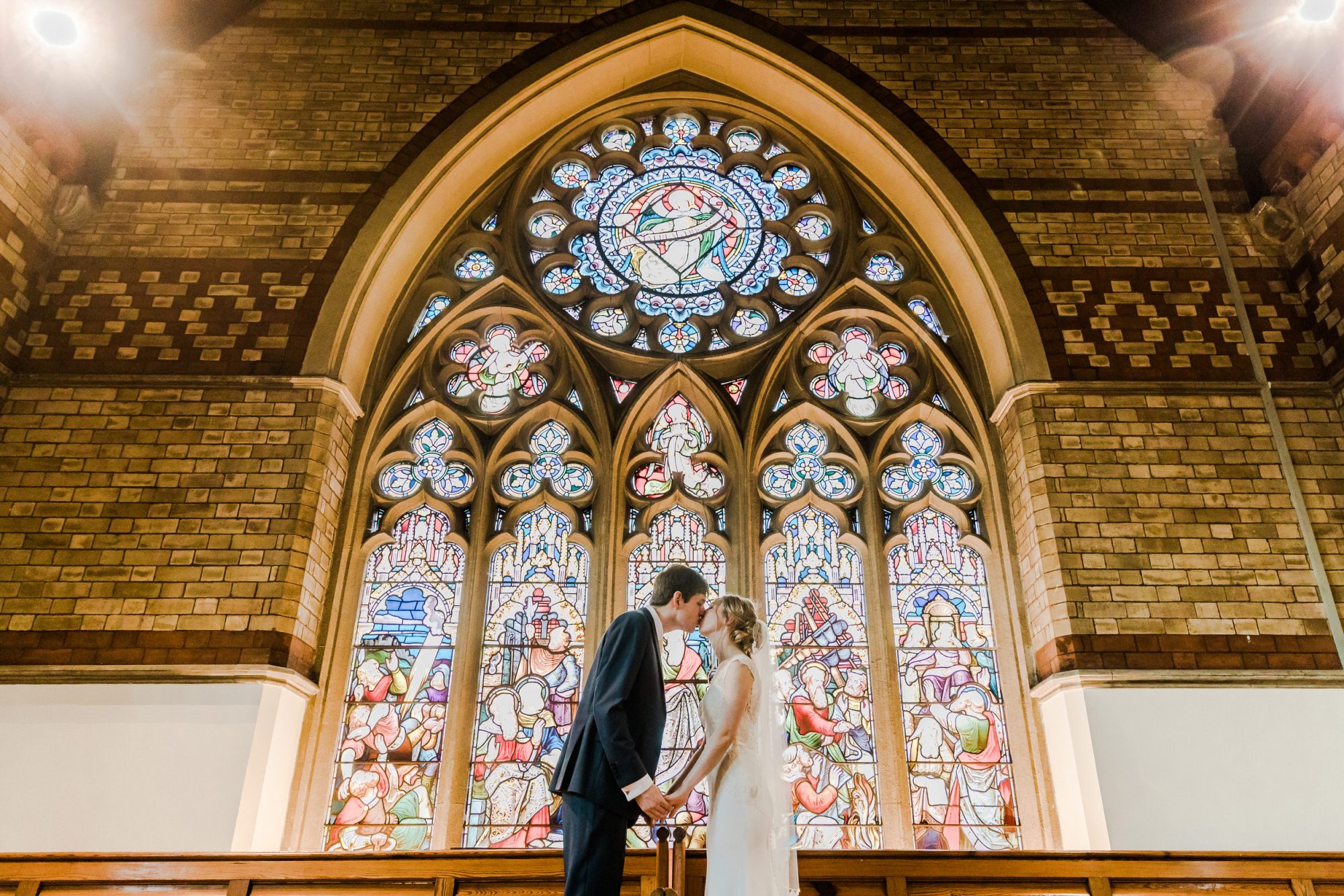 Bride Groom Kiss in front of Church Window St Pauls Church Leamington Spa Natural Wedding Photography Leamington Spa Relaxed Church Wedding