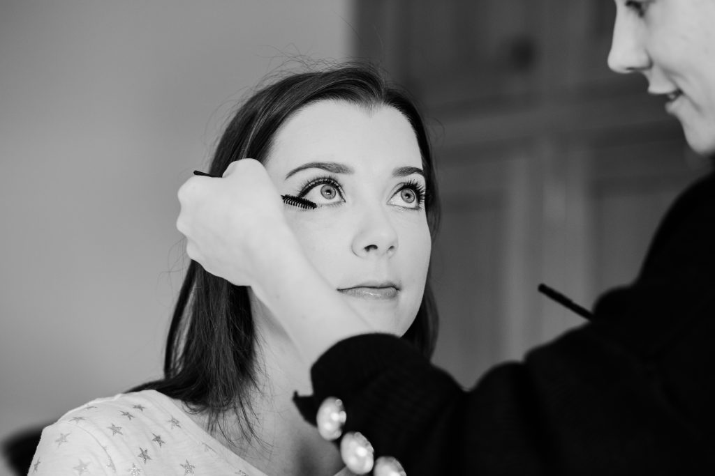 bride getting makeup applied on wedding morning Autumn barn wedding at swallows nest barn
