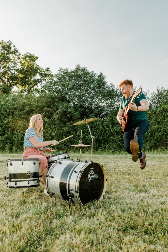music theme pre wedding shoot couple jam in feild at golden hour on guitar and drums
