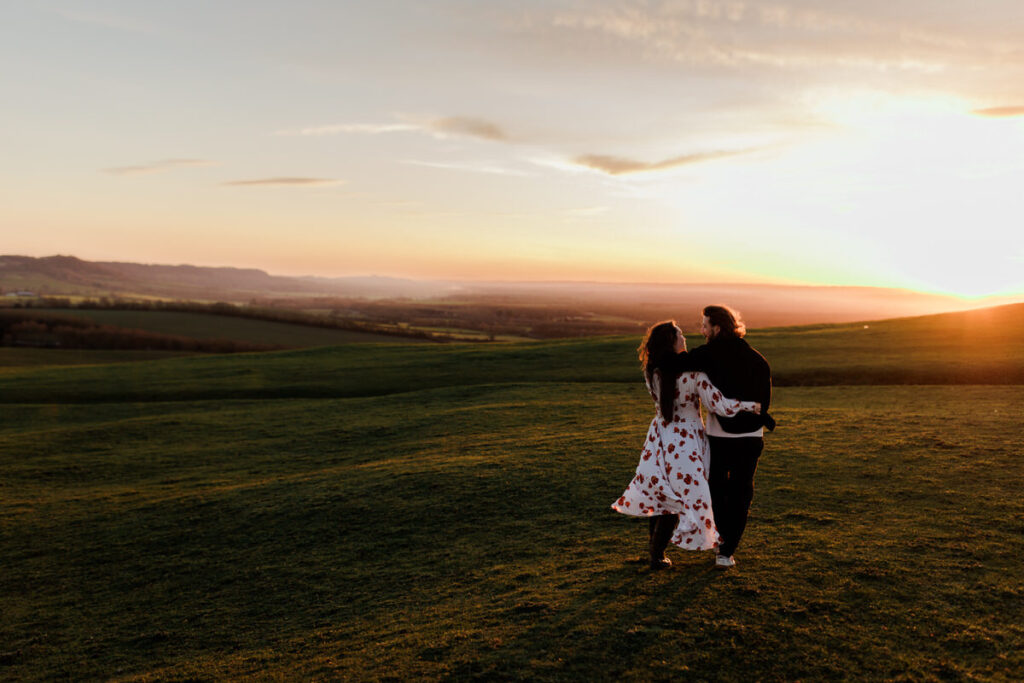 Pre wedding Shoot Warwickshire couple walk on hill at burton dasset at sunset